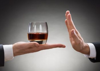 Close-up Of Businessman Hand Reject A Glass Of Whisky Offered By Businessperson